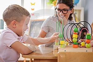Preschool teacher with children playing with colorful didactic toys at kindergarten