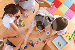 Preschool teacher with children playing with colorful wooden didactic toys at kindergarten