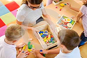 Preschool teacher with children playing with colorful didactic toys at kindergarten photo