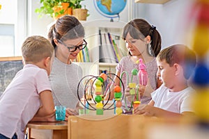 Preschool teacher with children playing with colorful didactic toys at kindergarten photo