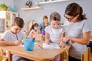 Preschool teacher looking at smart child at kindergarten