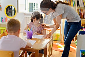 Preschool teacher looking at smart child at kindergarten