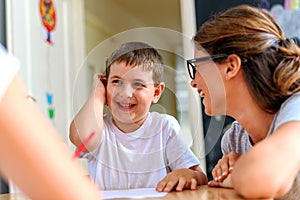 Preschool teacher looking at smart smiling boy at kindergarten