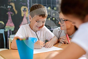 Preschool teacher looking at smart smiling boy at kindergarten