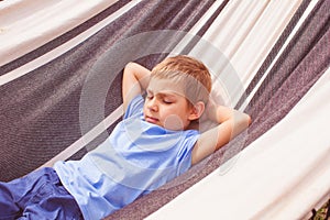 Preschoole boy lying in a hammock at summer day