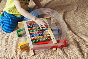 Preschooler baby learns to count. Cute child playing with abacus toy. Little boy having fun indoors at home