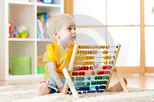 Preschooler baby learns to count. Cute child playing with abacus toy. Little boy having fun indoors at kindergarten