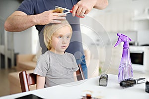 Preschooler boy gets haircut at home during quarantine. Hair cutting for kids by parents while hairdressers closed