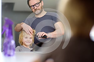 Preschooler boy gets haircut at home during quarantine. Reflection in mirror. Hair cutting for kids by parents while hairdressers