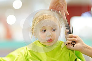 Preschooler boy getting haircut. Children hairdresser with professional tools - comb and scissors