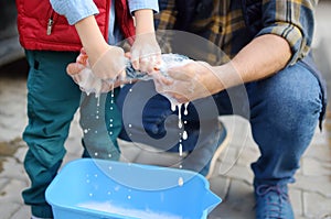 Preschooler boy helping his father washing family car. Little dad helper. Family with children spends time together