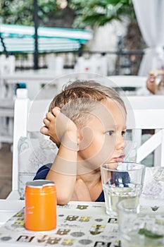 Preschooler boy sits in hotel restaurant waiting for order