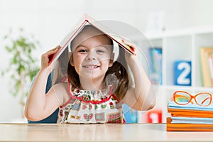 Preschooler child girl with book over her head