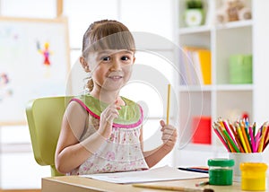 Preschooler child drawing and coloring by pencils photo