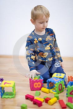 Preschooler child playing with colorful toy blocks. Kid playing with educational wooden toys