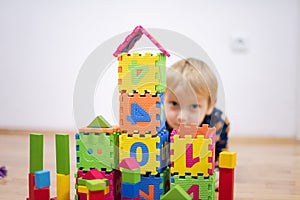 Preschooler child playing with colorful toy blocks. Kid playing with educational wooden toys