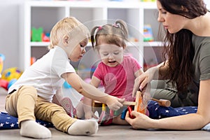 Preschooler children playing with educational wooden toys at kindergarten or day care center. Toddlers with teacher in photo