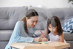 Preschooler girl entertain drawing picture with young mom