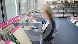 preschooler girl sitting on the floor in municipal library and reading a book
