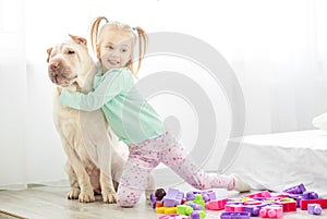 A preschooler hugs a big dog in the room.The concept of lifestyl