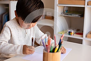 Preschooler kid drawing with coloured pencils. Homeschooling. Learning community. Montessori school