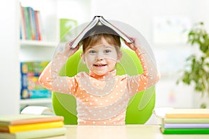 Preschooler kid girl with book over her head