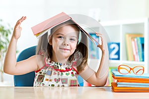 Preschooler kid girl with book over her head