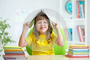 Preschooler kid girl with book over her head