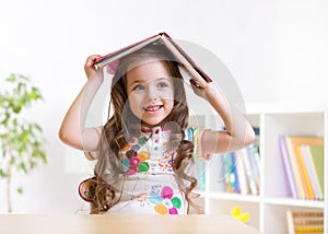Preschooler kid girl with book over her head photo