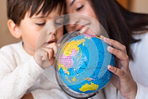 Preschooler Kid learing geography with a globe map and teacher educador help. Homeshooling. Learning Community. Montessori School