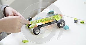 Preschooler kids playing with building blocks on table at home, make a model of spaceship or vehicle. Children assemble