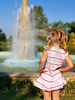 Preschooler little girl watching fountain rear view. Young female child enjoy being outside in summertime. Curiosity blonde