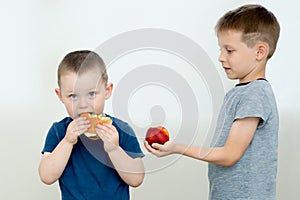 A preschooler offers a friend fruit instead of a hamburger, which he eats. the concept is to live a healthy lifestyle and eat