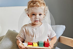 Preschooler\'s logical skills. Creative imagination play. Wavy haired little blonde baby girl palying with wooden sorter