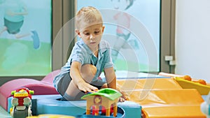 preschooler with shorts and light blue t-shirt playing with toys at the nursery, full shot