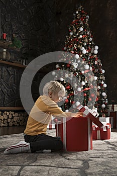 Prescooler blond boy open Christmas present. Surprised and joyful baby with great Xmas presents. Vertical frame