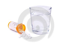 Prescription bottle and pills and glass of water isolated