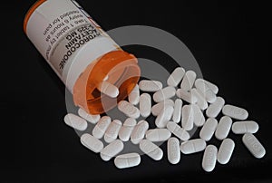 Prescription bottle and pills of opioids on black background