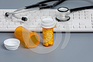 Prescription drugs and medication bottles with computer keyboard.