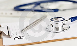 Prescription form clipped to pad lying on table with stethoscope