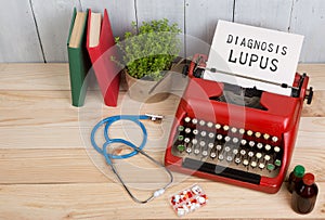 Prescription medicine or medical diagnosis - doctor workplace with stethoscope, pills, typewriter with text Diagnosis Lupus