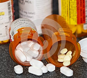 Prescription pill bottles on a black counter with pills spilling out