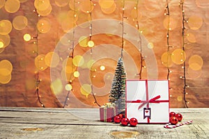Present box with Christmas decorations and bokeh lights on a wooden table