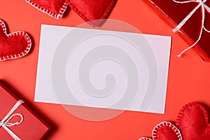 Present box with felt love hearts and greeting card on red paper background. Valentine`s day celebration concept. Top view. Flat