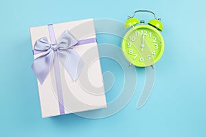 Present box and green clock on blue background pastel style copy