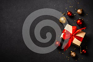 Present box and holiday decorations on black background.