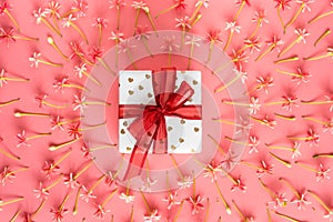 Present box with red bow on pink little flowers background.
