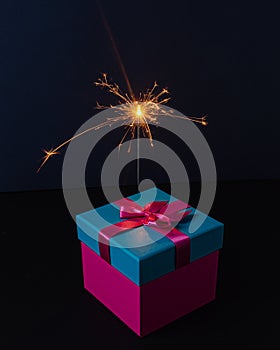 A present box with a sparkler on dark background