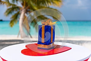 Present box on the table decorated with hearts for Saint Valentine\'s day holiday at the tropical beach near ocean