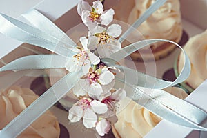 Present or gift box with cupcakes with delicate flowers from above. Holiday concept. Flat lay style, top view.